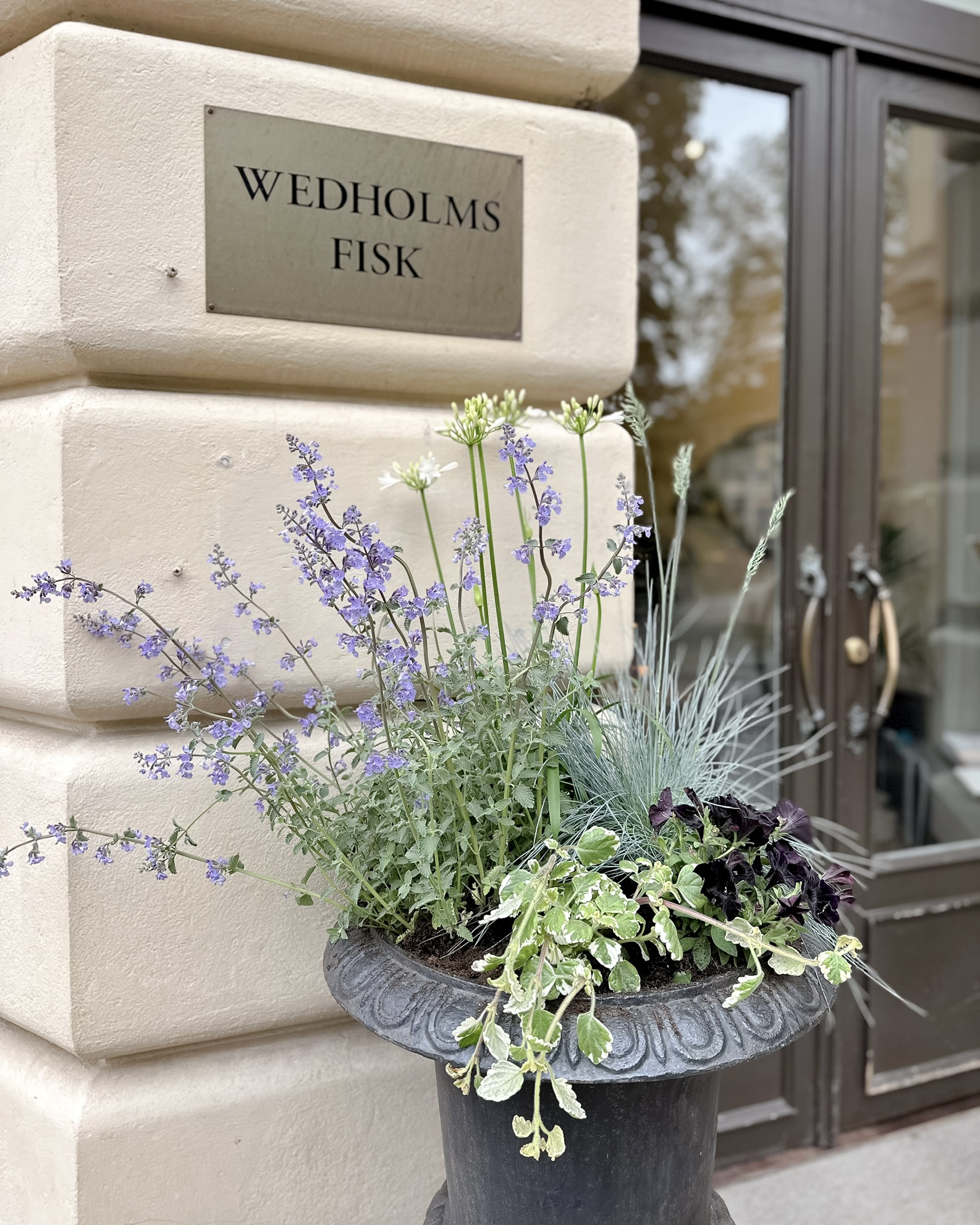 Planterare med blommor och bladverk vid en restaurangentré