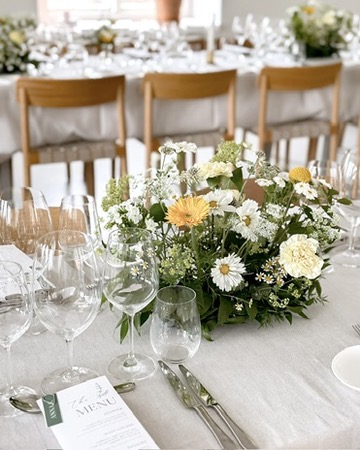 Bordsarrangemang i vitt och gult på festdukat bord
